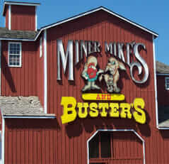 Miner Mike's sign made by mid state signs hanging up on a large, red barn.